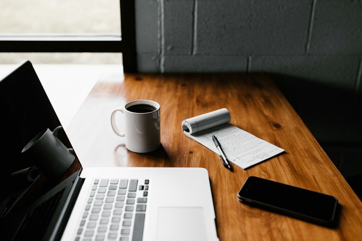 Laptop, coffee mug and paper pad on a desk